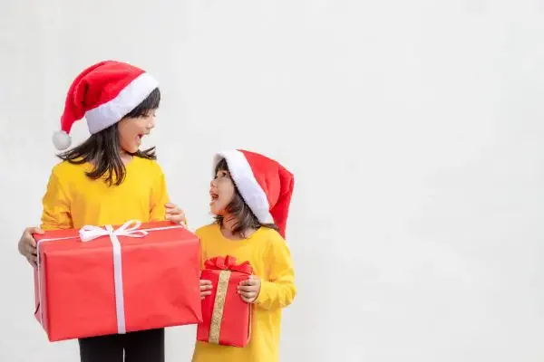 Two kids with Christmas hats and gifts in their hands