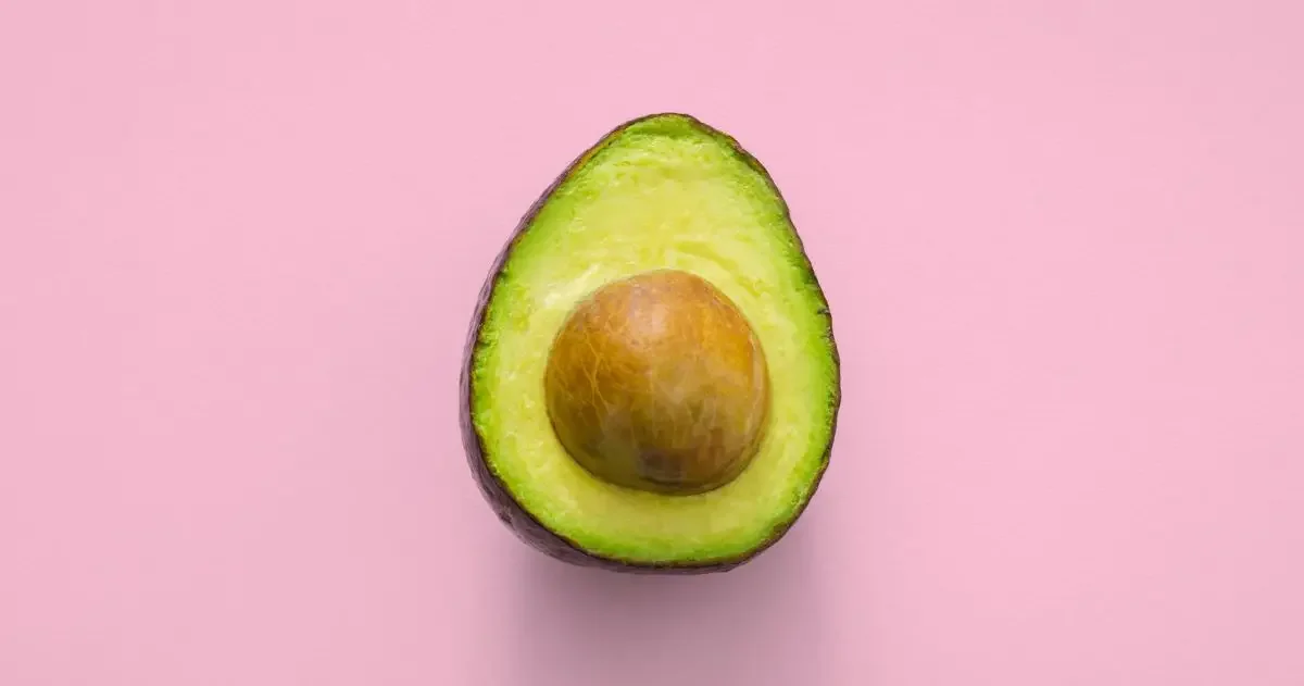 Half an avocado with a pink background