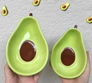 Two bowls that are shaped and decorated like avocados