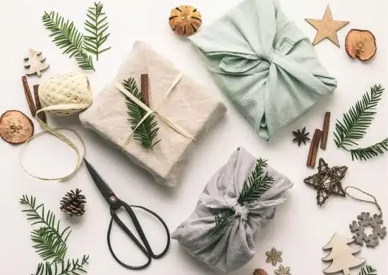 Three gifts wrapped in cloth with Christmas decorations