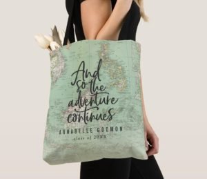 A woman wearing a tote bag with a world map and the quote "and so the adventure continues"