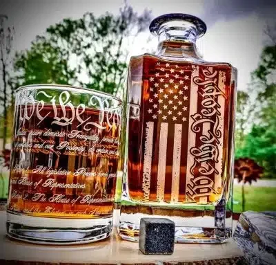 A decanter and a whiskey glass with "we the people" etched