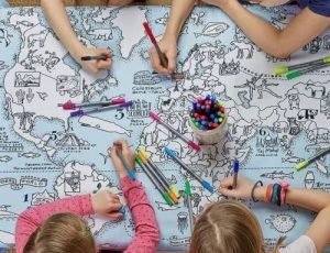 Children coloring on a tablecloth with the world map