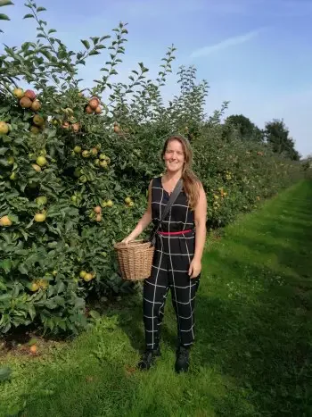 A woman holding a basket for fruit picking
