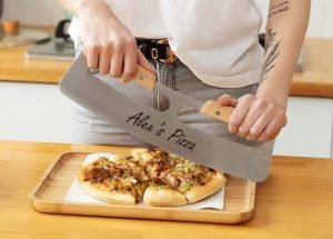 A woman cutting a pizza with an axe that is personalized