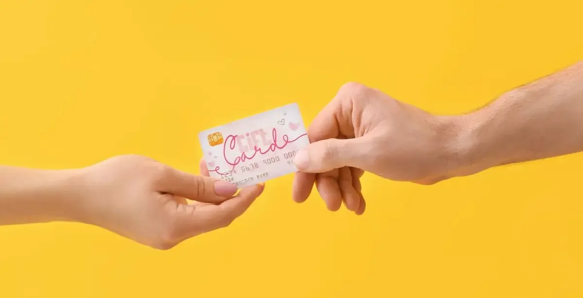 One hand giving a gift card to another hand