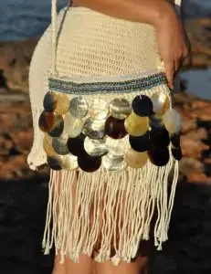 A women wearing a crochet sling bag decorated with pearls and fringes