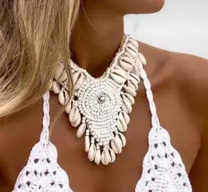 Woman wearing a large white necklace decorated with shells and beads