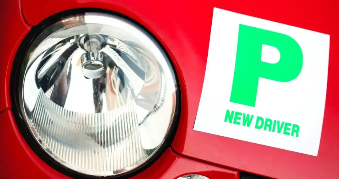 A headlight of a car with a sign for a new driver
