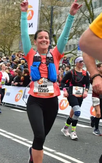 A woman holding her hands up and finishing a marathon
