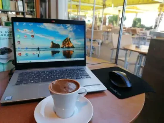 A cup of coffee with a laptop screensaver in the background