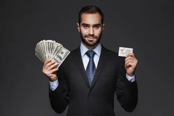An man holding cash in one hand and a gift card in the other